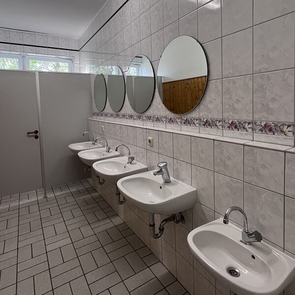 Waschbecken mit Spiegeln, im Vordergrund ein niedriges Kinderwaschbecken